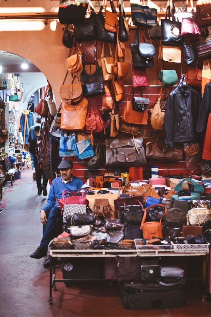 Services Vibrant leather goods display in a Moroccan market with a seated vendor.