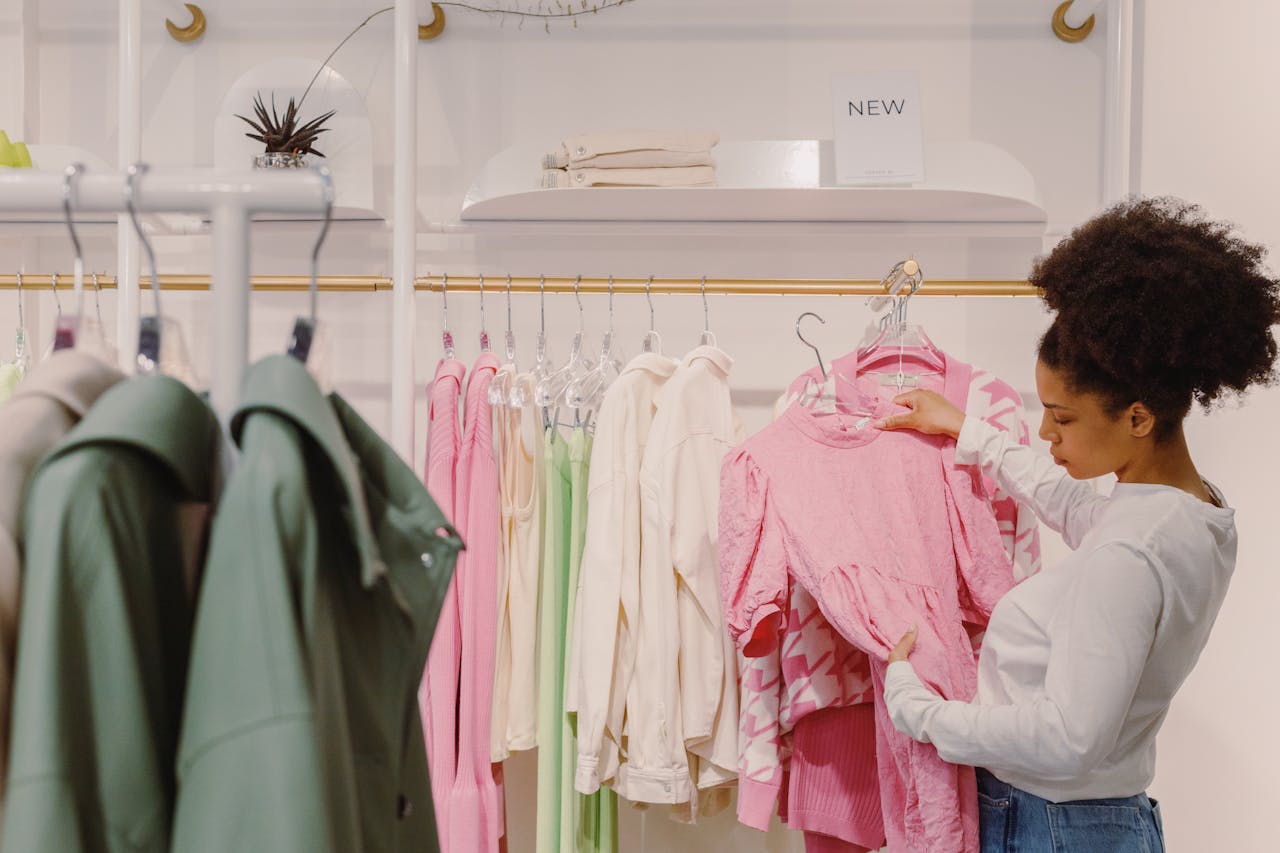 About A stylish woman explores pink and pastel outfits in a modern boutique.